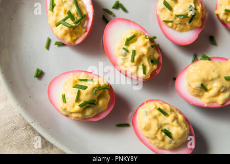 Homemade Pink Pickled Deviled Eggs with Chives Stock Photo