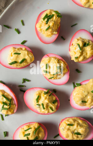 Homemade Pink Pickled Deviled Eggs with Chives Stock Photo