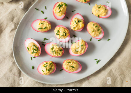 Homemade Pink Pickled Deviled Eggs with Chives Stock Photo