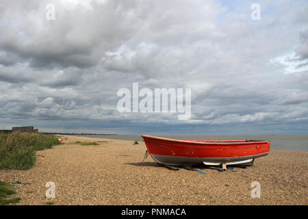 Red fishing boat on Dunwich Beach, Suffolk, England on a cloudy day Stock Photo