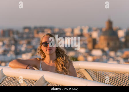 Young woman in sunglasses looks into the camera, Plaza de la Encarnacion, behind houses, Seville, Andalusia, Spain Stock Photo