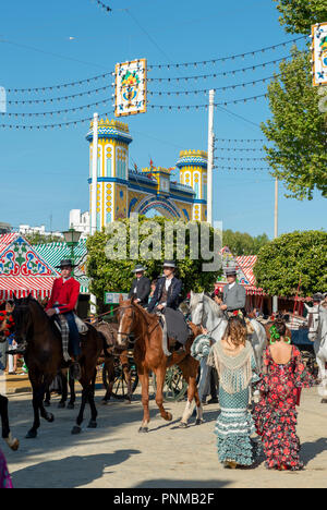 Spaniard in traditional flamenco dresses, horse-drawn carriage in front of Casetas, Feria de Abril, Seville, Andalusia, Spain Stock Photo