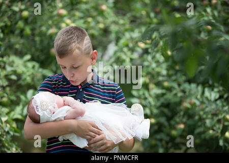 Belarus, Gomel, on July 14, 2018. A holiday in the village of Zyabrovka. Brother with a newborn sister in an apple orchard Stock Photo