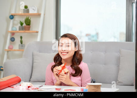 Happy young woman pressing gift box to her chest Stock Photo