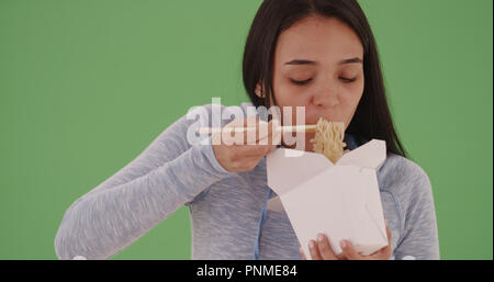 Young hispanic girl eating chinese food on green screen