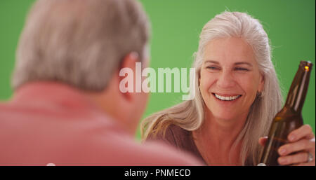 Mid aged white woman drinking a beer with a male companion on greenscreen Stock Photo