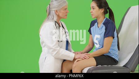 An injured soccer player seeks medical attention on green screen Stock Photo