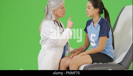 An injured soccer player seeks medical attention on green screen Stock Photo