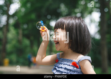 Portrait of funny lovely little girl blowing soap bubbles Stock Photo
