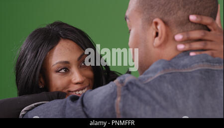Intimate couple sitting together looking into each others eyes on green screen Stock Photo