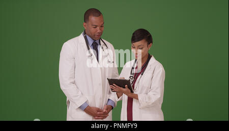 Two professional African American doctors with tablets on green screen Stock Photo