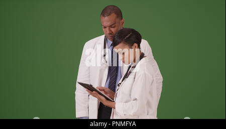 Two black medical professionals reviewing data on tablet device on green screen Stock Photo