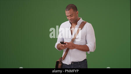 A young black man using mobile phone on green screen Stock Photo