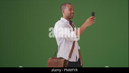 A young black man records video on his mobile phone on green screen Stock Photo