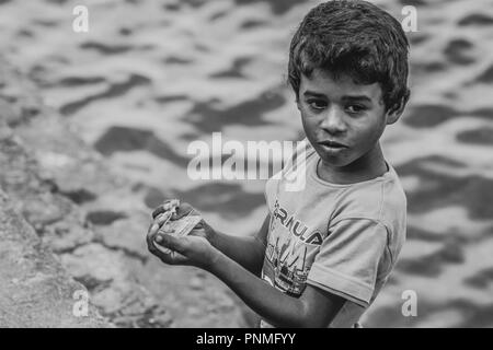 Sri lankan poor street kid counting money at Tissamaharama Stock Photo