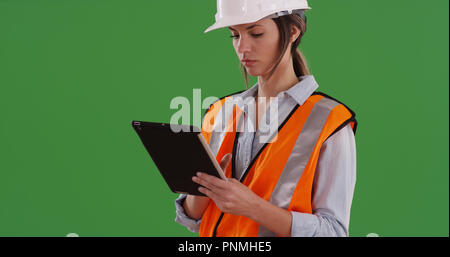 Woman worker in orange vest with tablet computer and hard hat on greenscreen Stock Photo