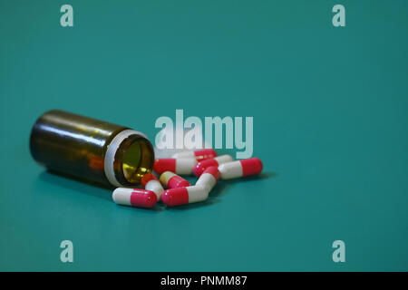 Medication capsules in an opened prescription bottle. Close-up of capsules on green background Stock Photo