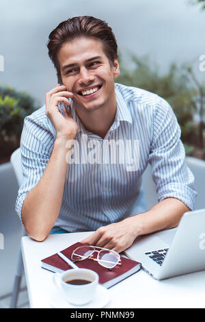 Smart attitude. Positive handsome man using a laptop and sitting in the cafe while surfing the internet. Stock Photo