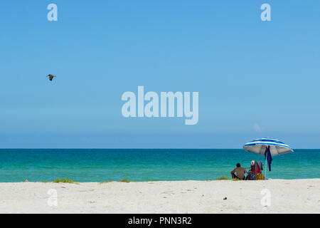 Yucatan beach. A couple of tourists under a beach umbrella at Chuburna, Yucatan, Mexico. Stock Photo