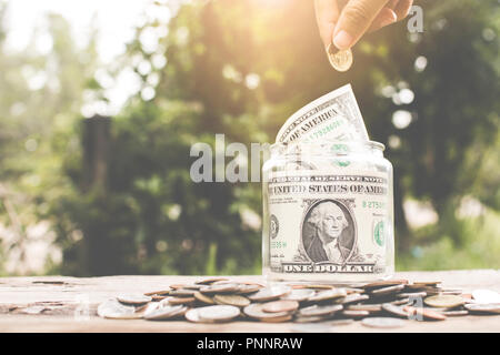 Save money concept, hand putting money coin in glass jar. Stock Photo