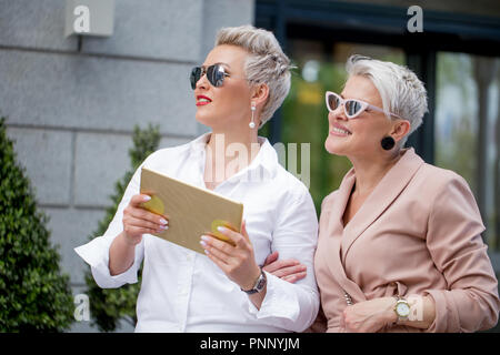 Two businesswoman walking on street near building. business woman going together with tablet computer Stock Photo