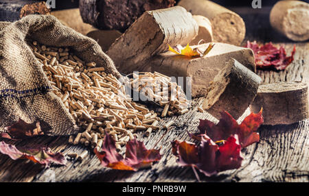 Wooden pressed pellets and briquettes from biomass with autumn leaves. Stock Photo