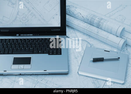 Laptop, graphic tablet and architectural plans. Picture in blue tint Stock Photo