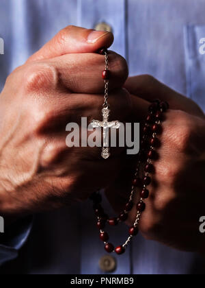 Hands holding rosary beads and cross while praying Stock Photo - Alamy