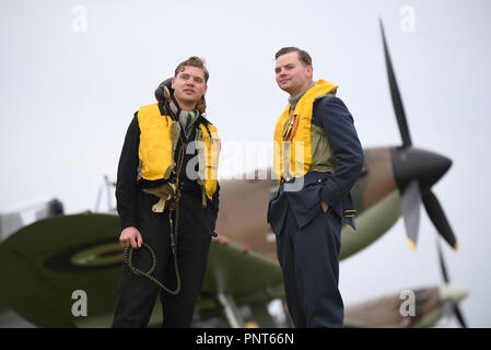 Historical reenactment members Jamie Delaney (left) and Gary Lewis from Spirit of Britain stand on the flight line in front of a Supermarine Spitfire prior to the Battle of Britain Air Show at the Imperial War Museum in Duxford, Cambridgeshire. Stock Photo