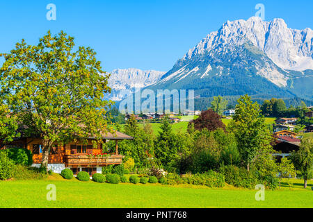 Traditional house on green meadow in Going am Wilden Kaiser mountain village, Kitzbuhel Alps, Austria Stock Photo