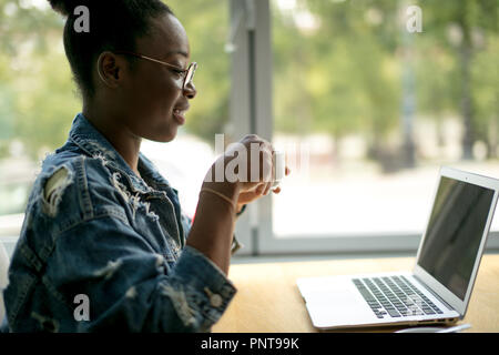 African female blogger, typing a new post during lunchtime at a cafe. Stock Photo