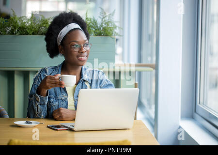 African female blogger, typing a new post during lunchtime at a cafe. Stock Photo