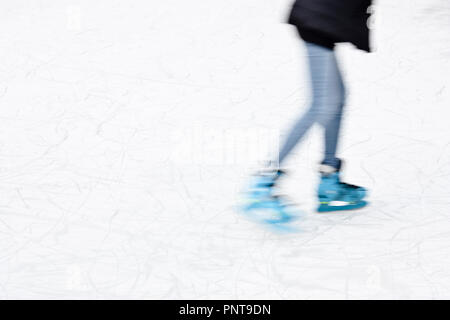 Young person ice skating, legs in motion blur in profile view Stock Photo