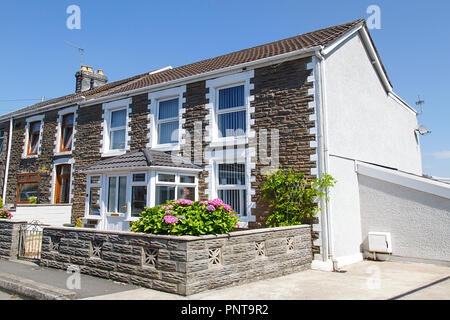Swansea, UK: July 07, 2018: Street view of typical double fronted terraced house in a Welsh village. Summertime with garden flowers and blue sky. Stock Photo