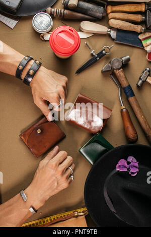Leather goods master and handmade leather wallets. Workflow in the workshop. Stock Photo