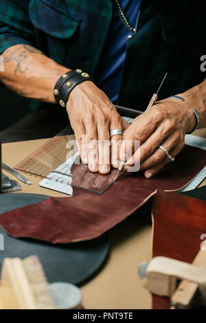 Leather goods master and handmade leather wallets. Workflow in the workshop. Stock Photo