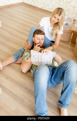 couple with book sitting on bed while moving into new home Stock Photo