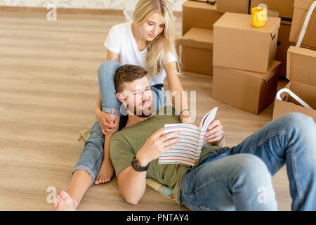 couple with book sitting on bed while moving into new home Stock Photo