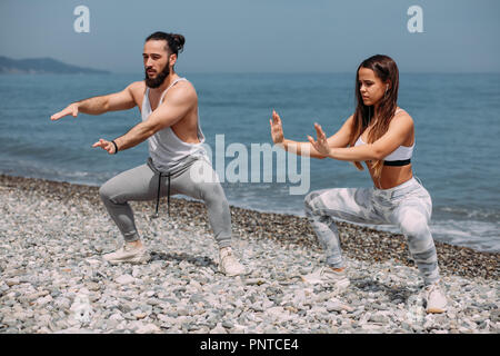 Couple warming out outdoors, doing squats together Stock Photo