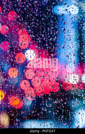 Bokeh lights of the Marina bay sands hotel and helix bridge shot through a  glass panel on a rainy night. darker red blue tone. Stock Photo