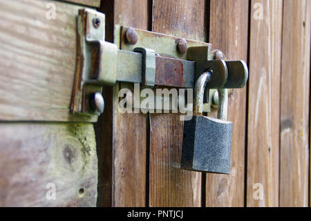 Rusted old padlock on hasp. Vintage lock protecting a wooden door. Stock Photo