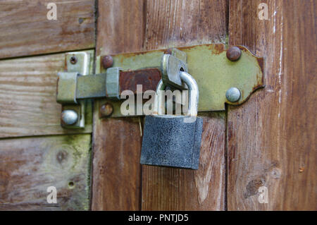 Rusted old padlock on latch. Vintage lock protecting a wooden door. Stock Photo