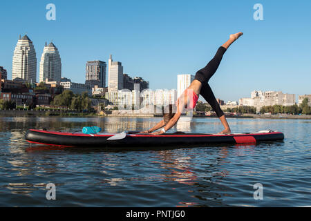 Woman doing yoga on sup board with paddle Stock Photo
