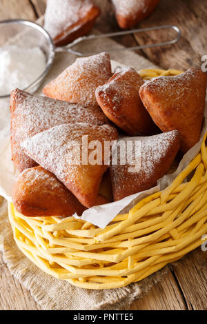 East African Mandazi  (dabo) donuts with powdered sugar close up in the basket on the table. vertical Stock Photo