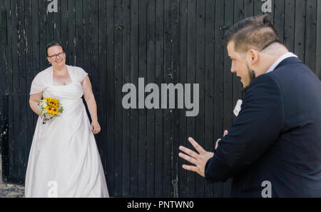 Bride is holding a bunch of flowers, groom is waiting to catch the bouquet Stock Photo