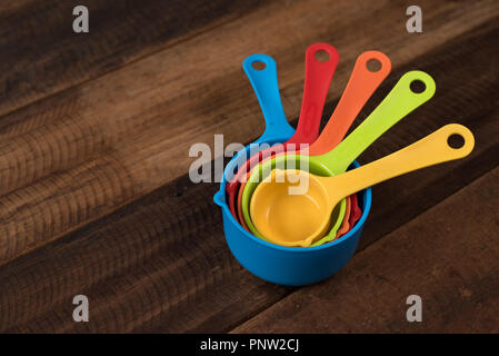 colorful measuring cups on a wooden table. Kitchen utensils concept Stock Photo