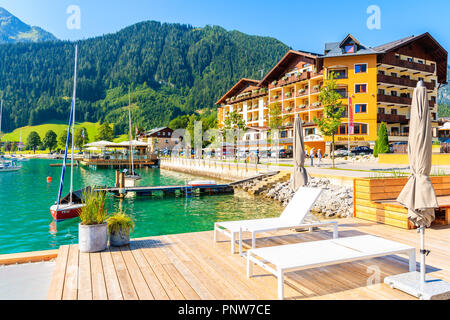 ACHENSEE LAKE, AUSTRIA - JUL 31, 2018: Young woman cyclist standing in Pertisau town on sunny summer day on shore of lake which is largest and deepest Stock Photo