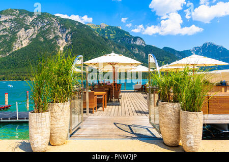 ACHENSEE LAKE, AUSTRIA - JUL 31, 2018: Restaurant on coastal promenade with flowers at Achensee lake on sunny summer day, Tirol. During summer this pl Stock Photo