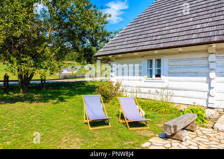 Two chairs on green lawn in front of a rural white house in Rabsztyn village near castle, Poland Stock Photo