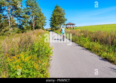 Young woman riding bike on cycling track around Tatra Mountains near Czarny Dunajec village. The end point is in Trstena village in Slovakia. Stock Photo